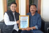 Ketua KANNI Kabupaten Bogor, Haidy Arsyad (kiri), menyerahkan Piagam Penghargaan KANNI Pratama Award kepada H. Mad Harun, Kepala Desa Cibodas, atas dedikasinya membangun masyarakat sadar hukum, Sabtu (24/5/2025).