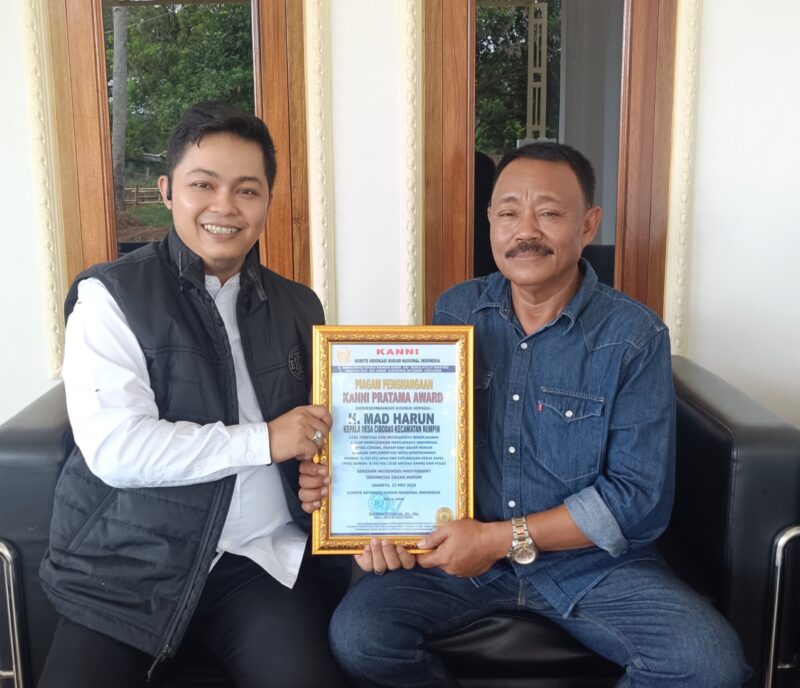 Ketua KANNI Kabupaten Bogor, Haidy Arsyad (kiri), menyerahkan Piagam Penghargaan KANNI Pratama Award kepada H. Mad Harun, Kepala Desa Cibodas, atas dedikasinya membangun masyarakat sadar hukum, Sabtu (24/5/2025).