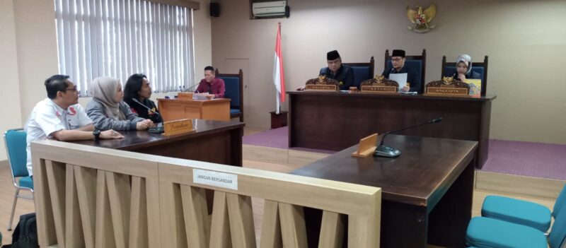 Ilham, Ketua KANNI Kabupaten Cianjur (berambut gondrong, berkemeja hitam), saat mengikuti persidangan di hadapan majelis Komisi Informasi Provinsi Jawa Barat, Senin (23/6/2025)./Dok.kanniadvokasi.id