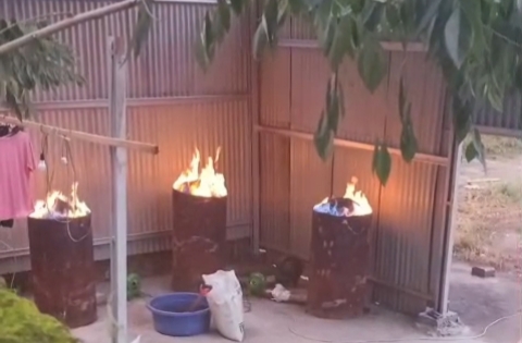 Tiga drum berisi material terbakar mengeluarkan api di sebuah bangunan berdinding seng, diduga digunakan untuk pembakaran bahan kimia dalam aktivitas pengolahan emas ilegal di Kelurahan Kotabangun, Kotamobagu Timur. (Foto: Dok. Warga)