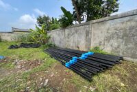 Tumpukan tiang dan kabel milik PT Handayani Fiber yang rencananya akan dipasang di wilayah Desa Tugu Jaya tanpa izin resmi dari warga dan perangkat lingkungan.