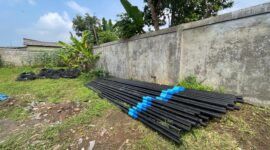 Tumpukan tiang dan kabel milik PT Handayani Fiber yang rencananya akan dipasang di wilayah Desa Tugu Jaya tanpa izin resmi dari warga dan perangkat lingkungan.